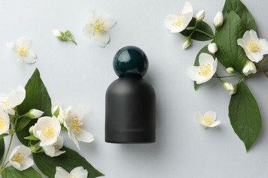 Photo of Bottle of perfume and jasmine flowers on light background, flat lay