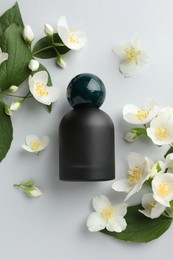 Photo of Bottle of perfume and jasmine flowers on light background, flat lay