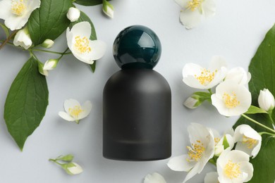 Photo of Bottle of perfume and jasmine flowers on light background, flat lay