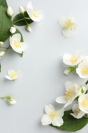 Photo of Beautiful jasmine flowers with leaves on light background, flat lay. Space for text