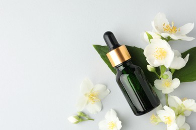 Photo of Cosmetic product and jasmine flowers on light background, flat lay. Space for text