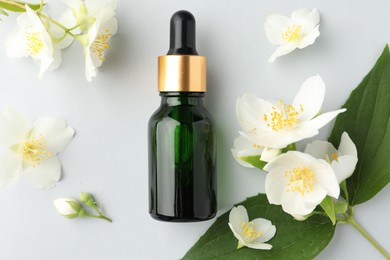 Photo of Cosmetic product and jasmine flowers on light background, flat lay