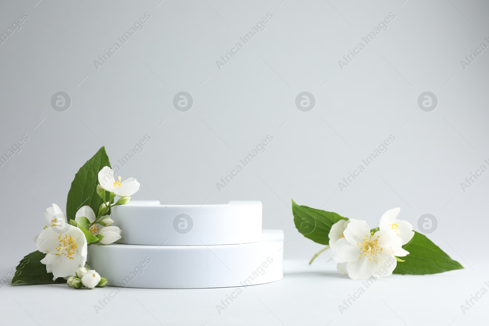 Beautiful jasmine flowers with leaves on light background. Space for text Photo of Beautiful jasmine flowers with leaves on light background. Space for text