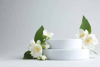 Photo of Beautiful jasmine flowers with leaves on light background. Space for text