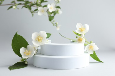 Photo of Beautiful jasmine flowers with leaves on light background