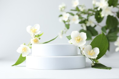 Photo of Beautiful jasmine flowers with leaves on light background