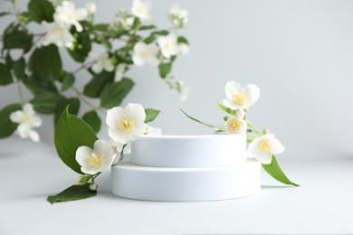 Photo of Beautiful jasmine flowers with leaves on light background