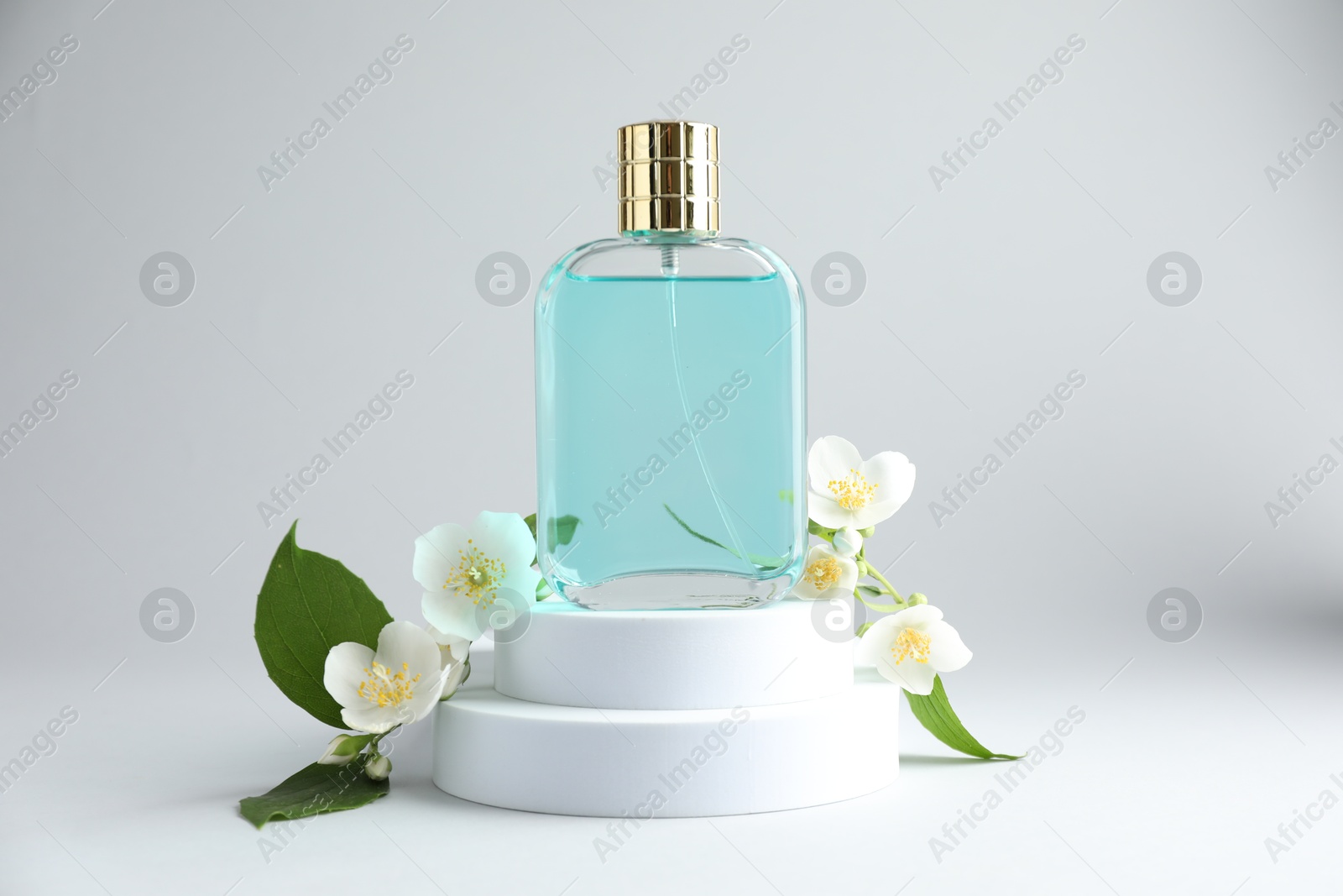 Bottle of perfume and jasmine flowers on light background Photo of Bottle of perfume and jasmine flowers on light background