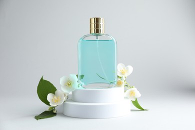 Photo of Bottle of perfume and jasmine flowers on light background