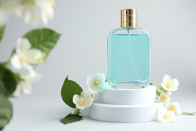 Photo of Bottle of perfume and jasmine flowers on light background, closeup. Space for text