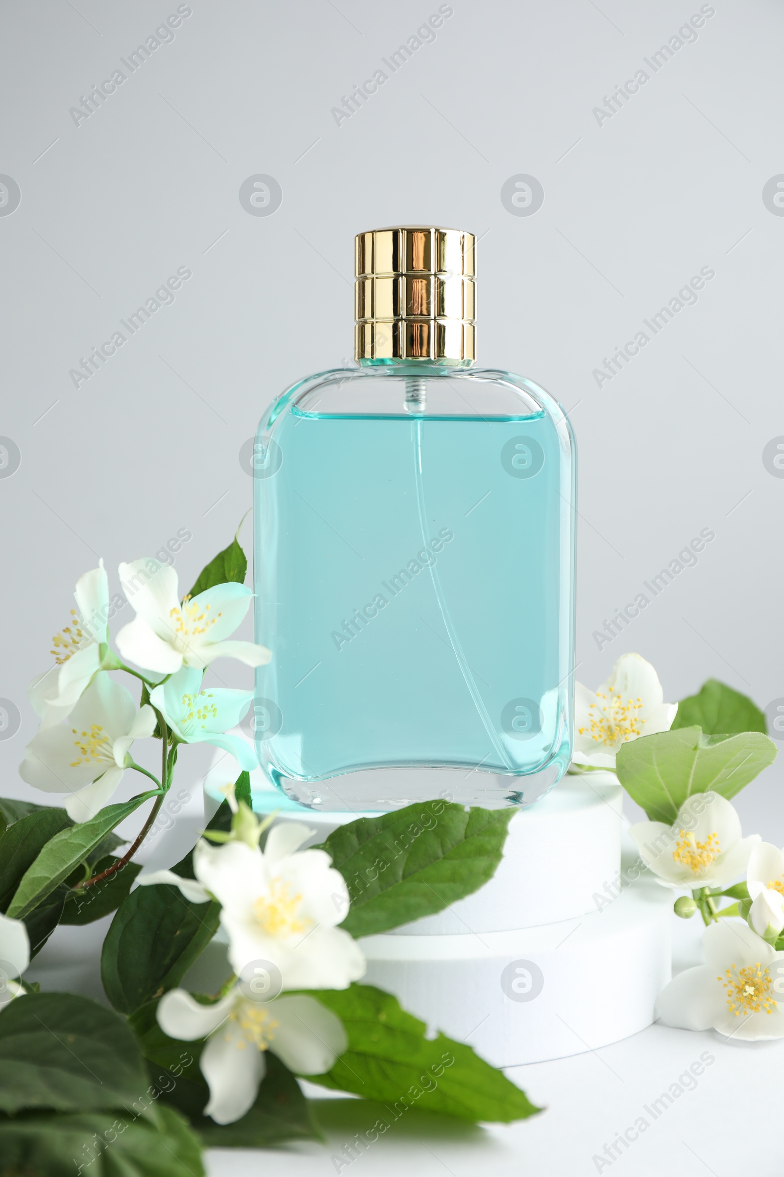Bottle of perfume and jasmine flowers on light background, closeup Photo of Bottle of perfume and jasmine flowers on light background, closeup
