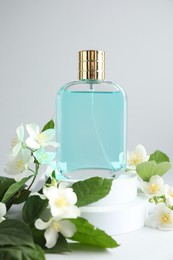 Photo of Bottle of perfume and jasmine flowers on light background, closeup