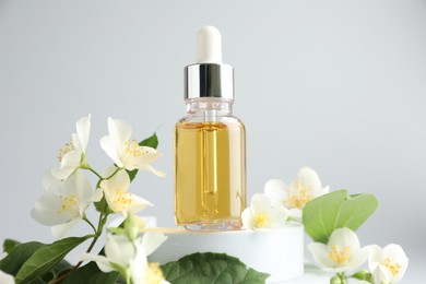 Photo of Cosmetic product and jasmine flowers on light background, closeup
