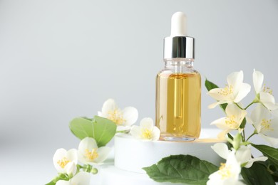 Photo of Cosmetic product and jasmine flowers on light background, closeup. Space for text