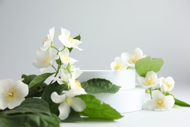 Photo of Beautiful jasmine flowers with leaves on light background, closeup
