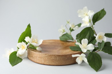 Photo of Beautiful jasmine flowers with leaves on light background. Space for text