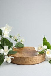 Photo of Beautiful jasmine flowers with leaves on light background. Space for text