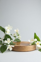 Photo of Beautiful jasmine flowers with leaves on light background. Space for text