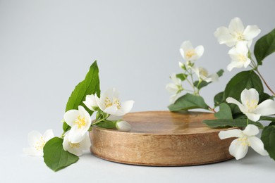 Photo of Beautiful jasmine flowers with leaves on light background, closeup. Space for text