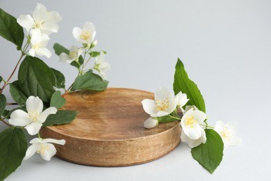 Photo of Beautiful jasmine flowers with leaves on light background, closeup. Space for text
