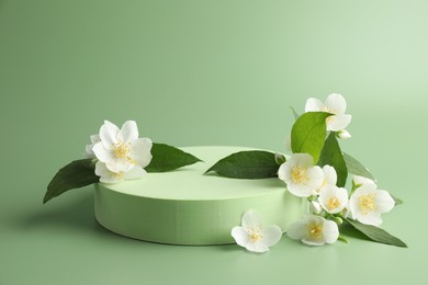 Photo of Beautiful jasmine flowers with leaves on green background. Space for text