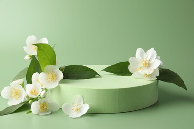 Photo of Beautiful jasmine flowers with leaves on green background. Space for text