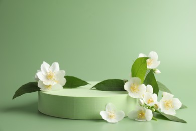 Photo of Beautiful jasmine flowers with leaves on green background. Space for text