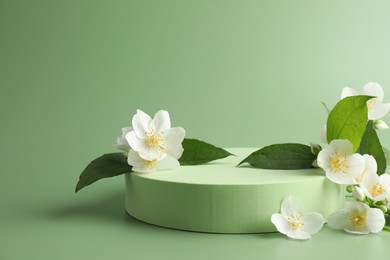 Photo of Beautiful jasmine flowers with leaves on green background. Space for text