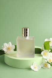 Photo of Bottle of perfume and jasmine flowers on green background. Space for text