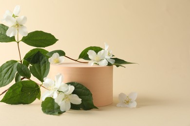 Photo of Beautiful jasmine flowers with leaves on beige background. Space for text