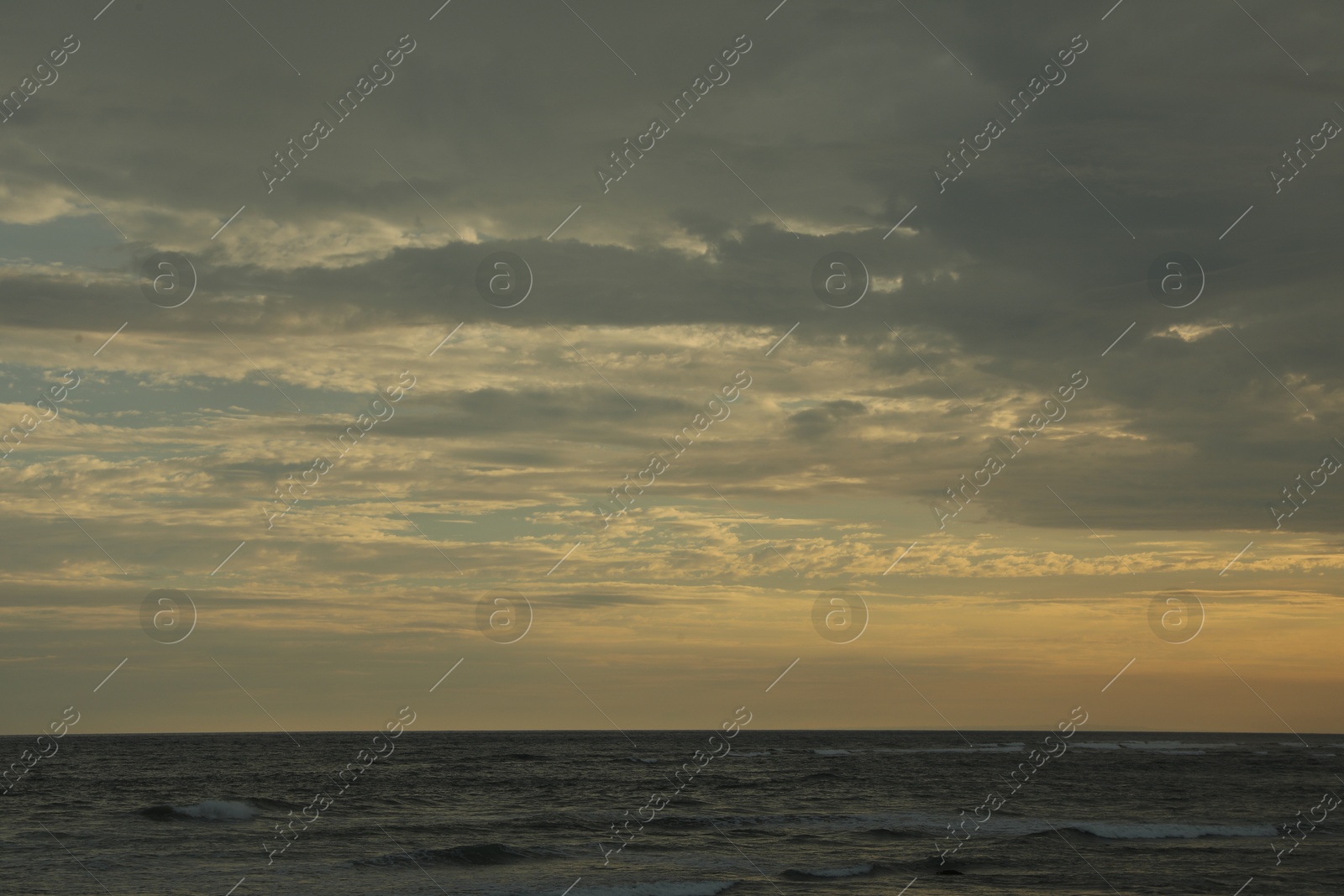 Beautiful wavy sea under cloudy sky at sunset Photo of Beautiful wavy sea under cloudy sky at sunset