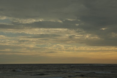 Photo of Beautiful wavy sea under cloudy sky at sunset