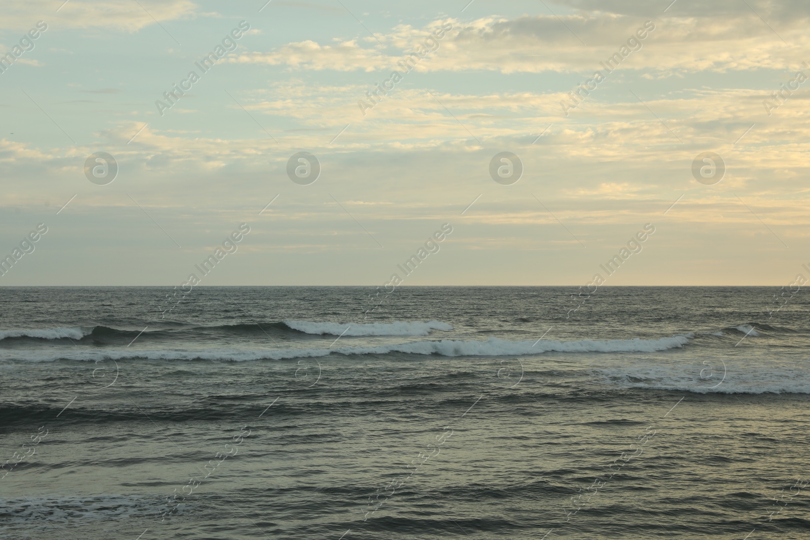 Beautiful wavy sea under cloudy sky at sunset Photo of Beautiful wavy sea under cloudy sky at sunset
