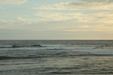 Photo of Beautiful wavy sea under cloudy sky at sunset