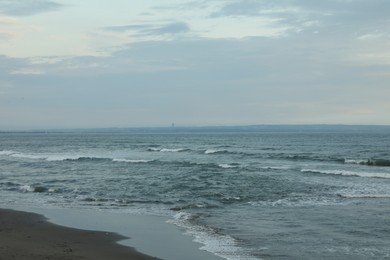 Photo of Beautiful wavy sea and sandy beach under blue sky