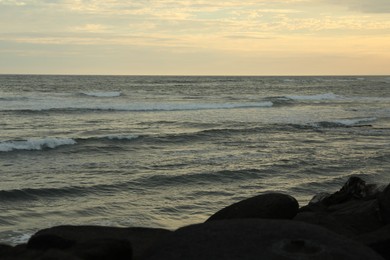 Photo of Beautiful wavy sea and rocky beach at sunset