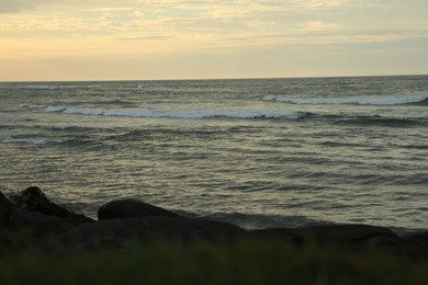 Photo of Beautiful wavy sea and rocky beach at sunset