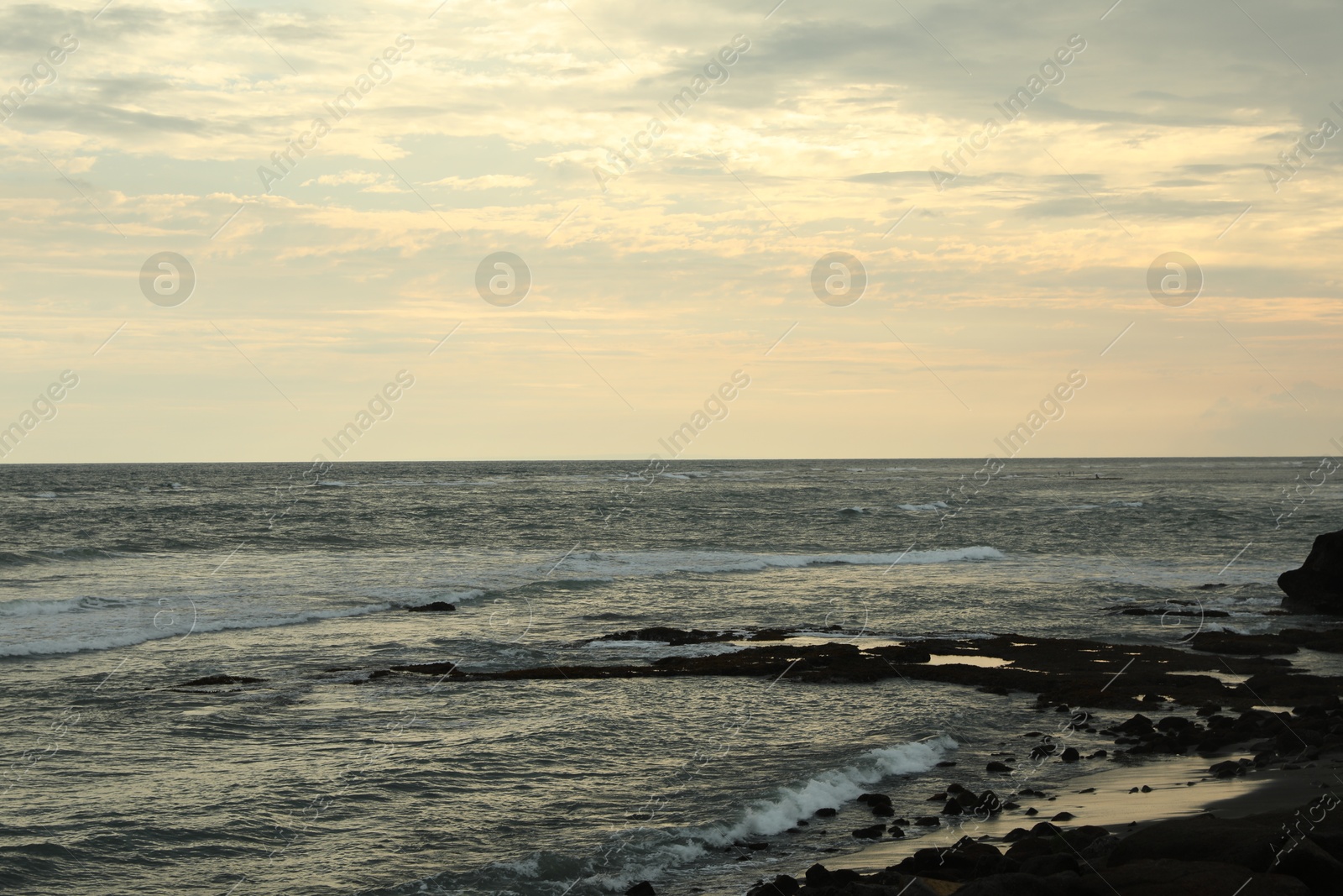 Beautiful wavy sea and rocky beach at sunset Photo of Beautiful wavy sea and rocky beach at sunset