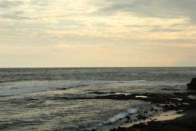 Photo of Beautiful wavy sea and rocky beach at sunset