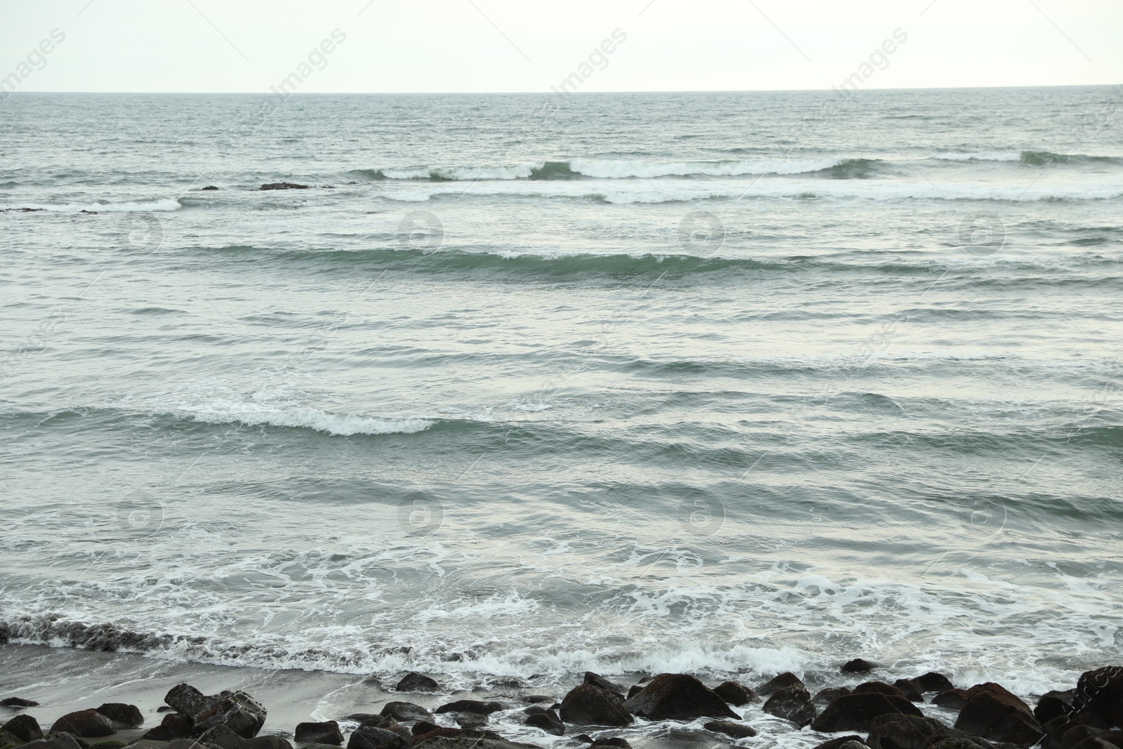 View of beautiful wavy sea and many stones Photo of View of beautiful wavy sea and many stones