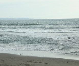 Photo of View of beautiful wavy sea and sandy beach