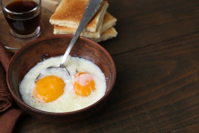 Photo of Half-boiled eggs in bowl, soy sauce and toasted bread on wooden table, closeup. Space for text
