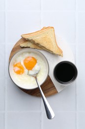 Photo of Half-boiled eggs in bowl, soy sauce and toasted bread on white tiled table, flat lay
