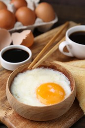 Photo of Half-boiled egg in bowl, soy sauce, chopsticks, coffee and toasted bread on table, closeup