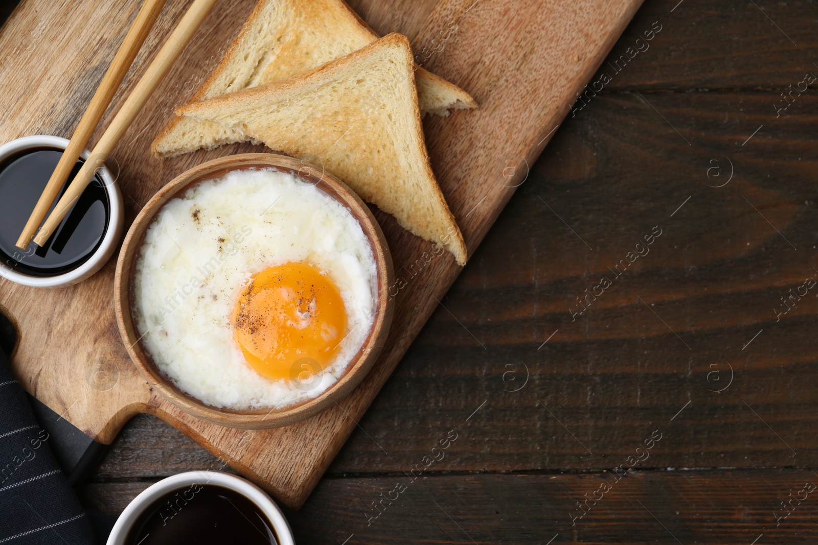 Half-boiled egg in bowl, soy sauce, chopsticks, coffee and toasted bread on wooden table, flat lay. Space for text Photo of Half-boiled egg in bowl, soy sauce, chopsticks, coffee and toasted bread on wooden table, flat lay. Space for text