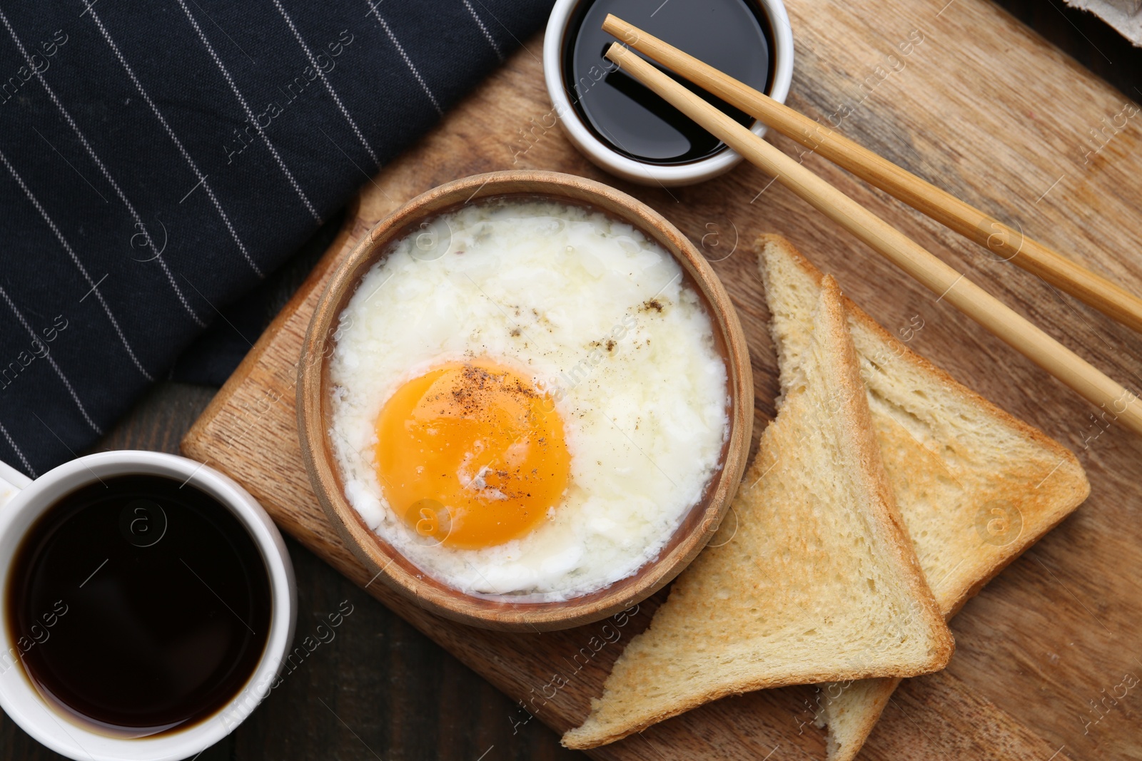 Half-boiled egg in bowl, soy sauce, chopsticks, coffee and toasted bread on wooden table, flat lay Photo of Half-boiled egg in bowl, soy sauce, chopsticks, coffee and toasted bread on wooden table, flat lay