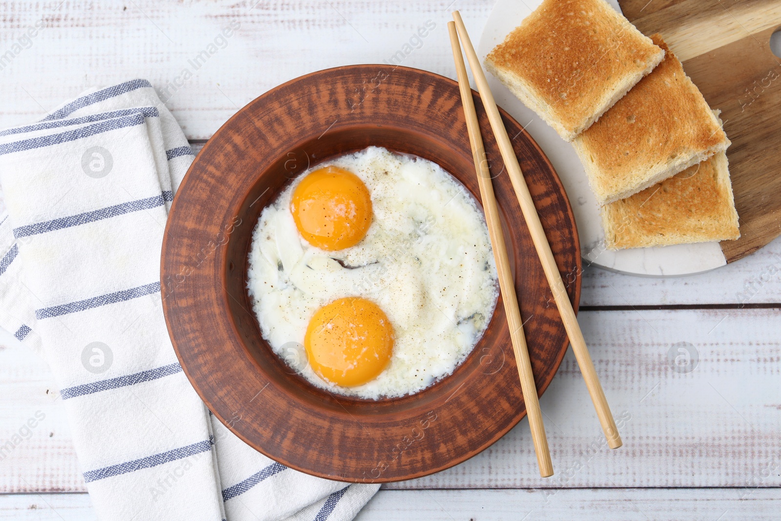 Half-boiled eggs in plate, chopsticks and toasted bread on white wooden table, flat lay Photo of Half-boiled eggs in plate, chopsticks and toasted bread on white wooden table, flat lay