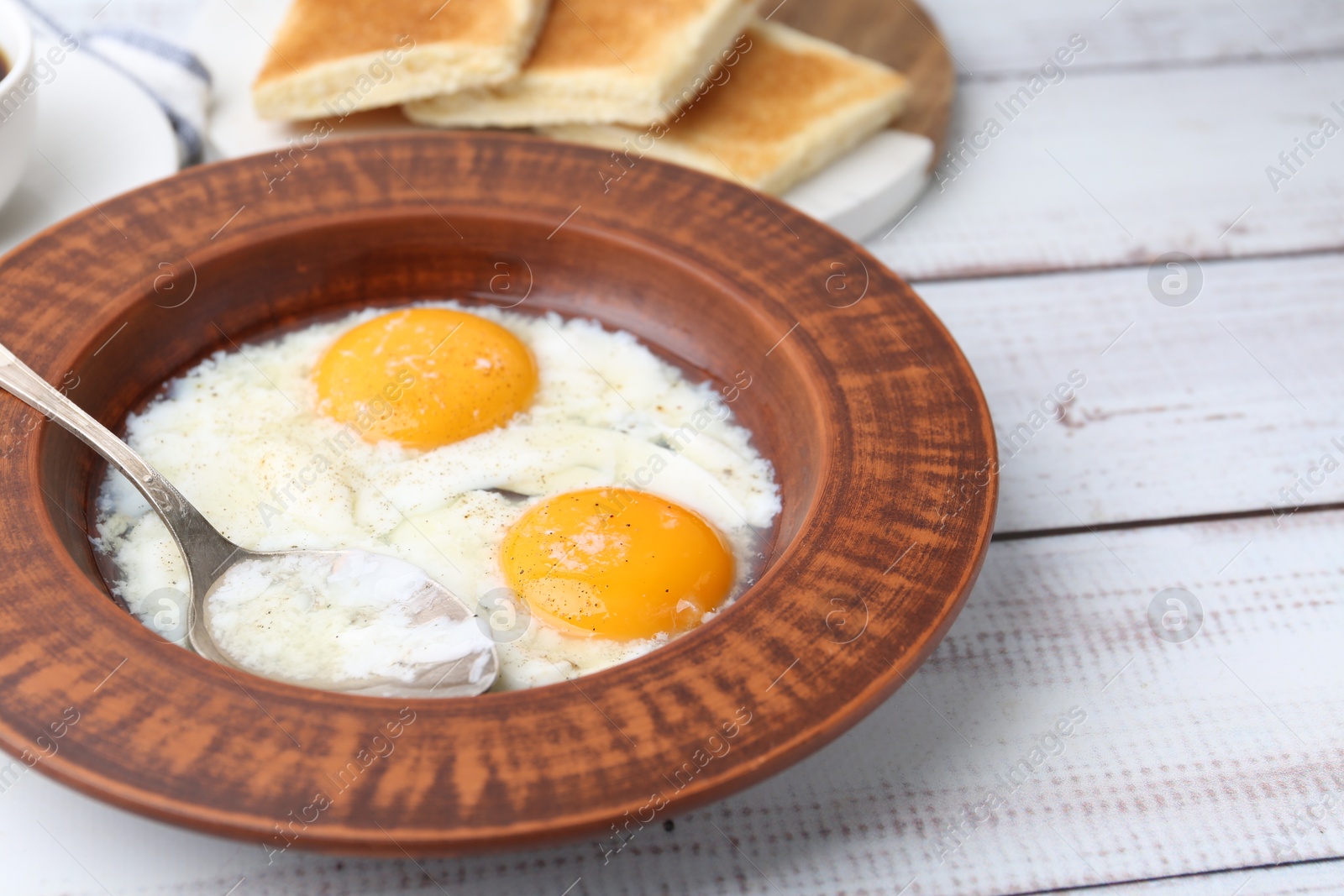 Half-boiled eggs in plate, spoon and toasted bread on white wooden table, closeup Photo of Half-boiled eggs in plate, spoon and toasted bread on white wooden table, closeup