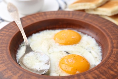 Photo of Half-boiled eggs in plate and spoon on table, closeup