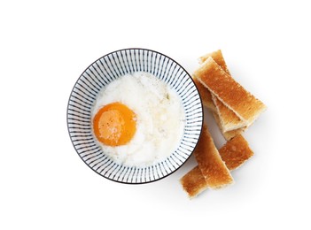 Photo of Half-boiled egg in bowl and toasted bread isolated on white, top view